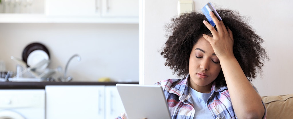 Stressed woman holding credit card and tablet, trying to figure out what to do after identity theft