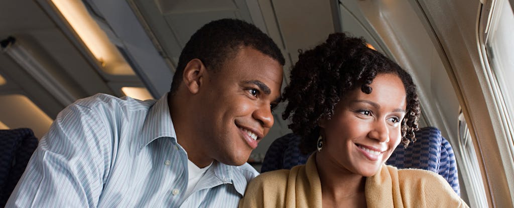 Smiling couple on an airplane looks out the window, happy that they maximized their Delta Air Line rewards