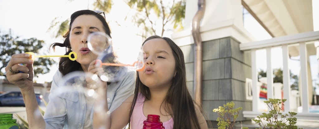 Grandmother and granddaughter blowing bubbles on summer porch