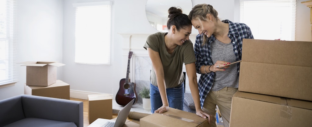 Affectionate female couple surrounded by moving boxes living room