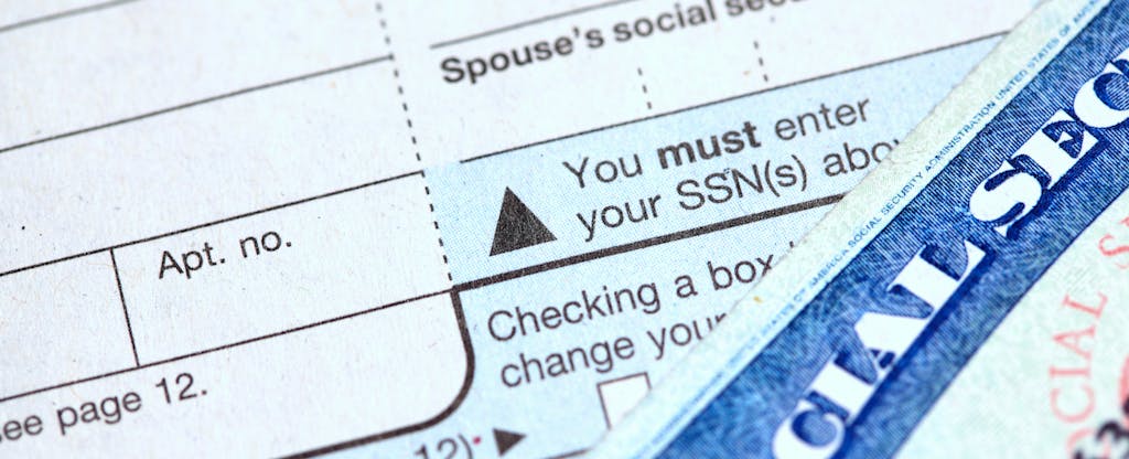 Close shot of the Social Security number field of a 1040 tax form, and the corner of a Social Security card.