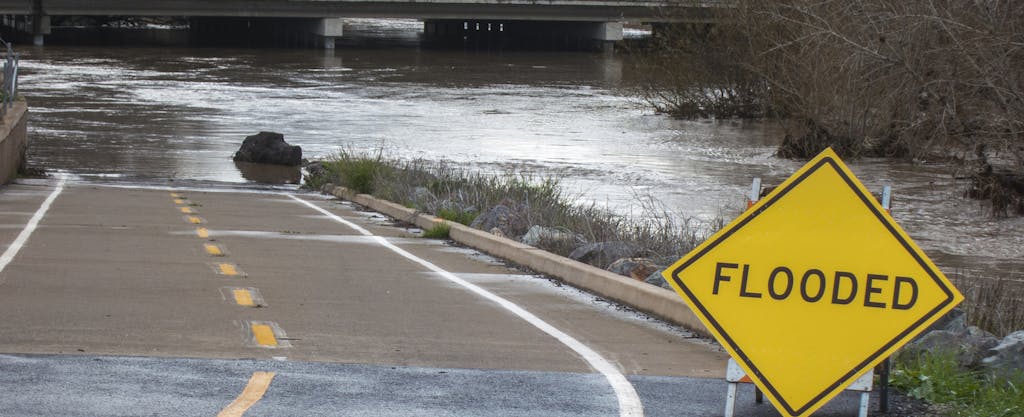 Flooded roadway with "flooded" sign