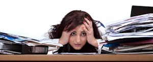 Young hispanic woman, leaning her head on desk in frustration, trying to decide how long to keep tax records.