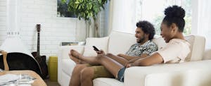 Casual couple relaxing watching TV in living room