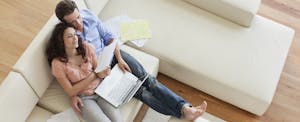 Couple sitting on sofa paying bills together
