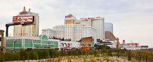 The boardwalk and skyline of Atlantic City, New Jersey with sand dunes and beach grasses in the foreground.