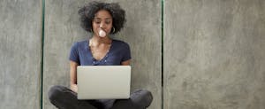 College student using laptop and blowing bubble gum bubble