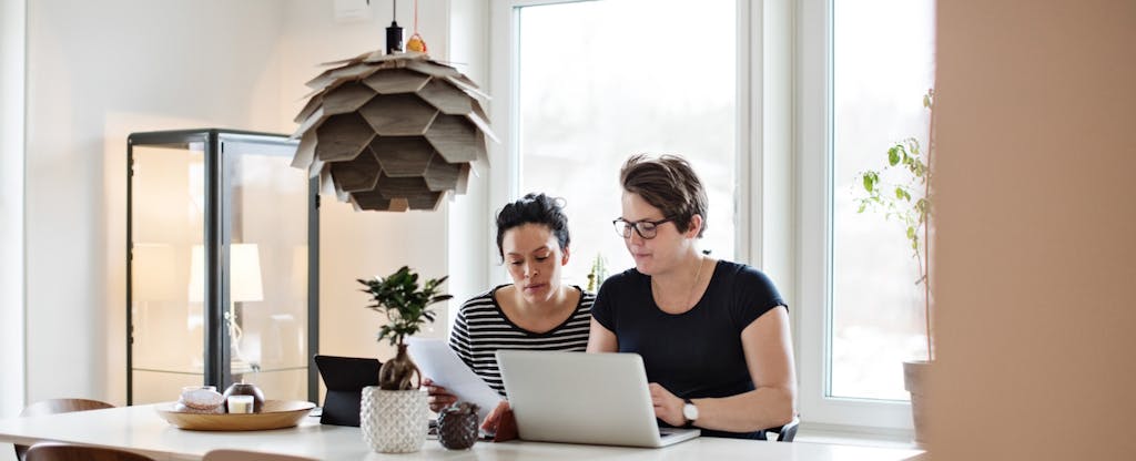 Women discussing financial bills over laptop while sitting at table