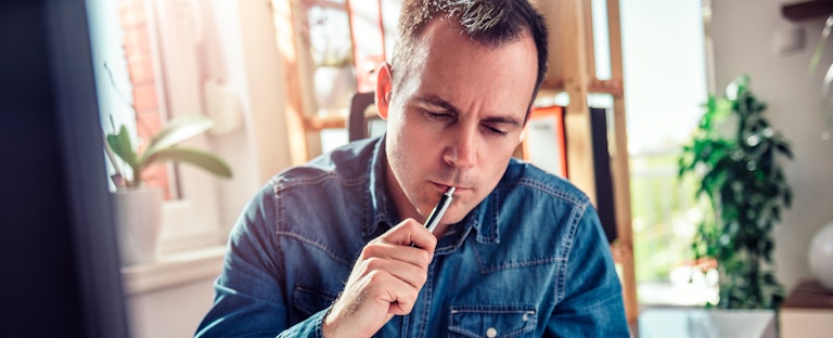 Worried businessman wearing blue jean shirt sitting by the window at the desk reading mail in the office