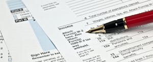 Various tax forms with a pen
