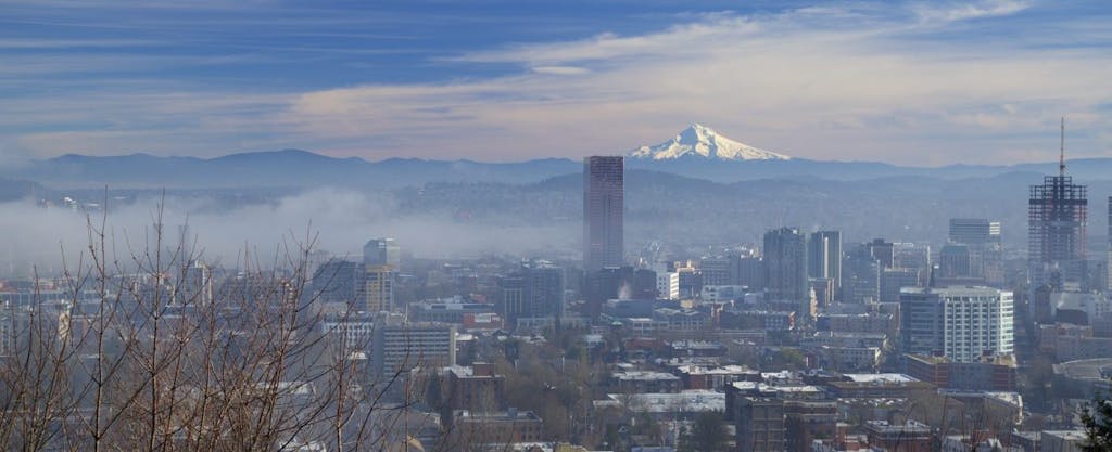 Morning fog hovers over downtown Portland, Oregon with Mt. Hood in the background.