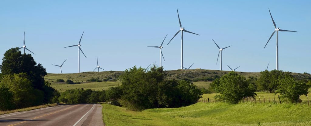 Wind turbines rise above rolling green fields in Oklahoma, making power from the states notorious weather patterns.