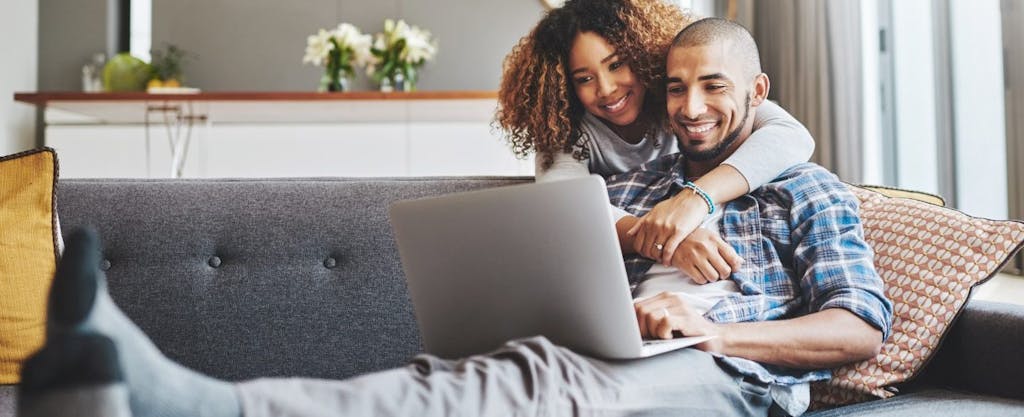 African American couple using laptop to e-file their taxes, smiling confidently.