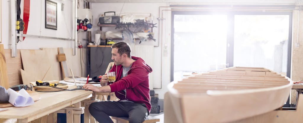 Male carpenter working at laptop in workshop