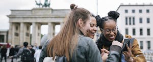 A group of friends visiting Berlin are laughing as they look at a smartphone