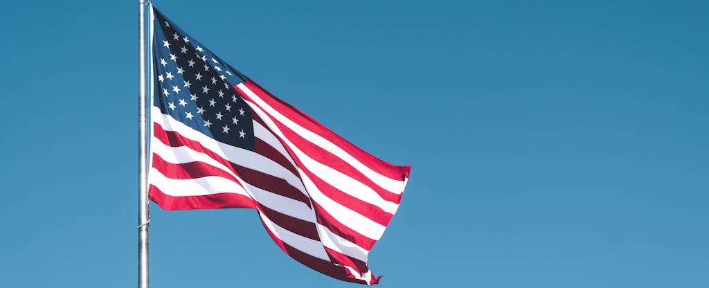 Low Angle View Of American Flag Waving Against Clear Blue Sky