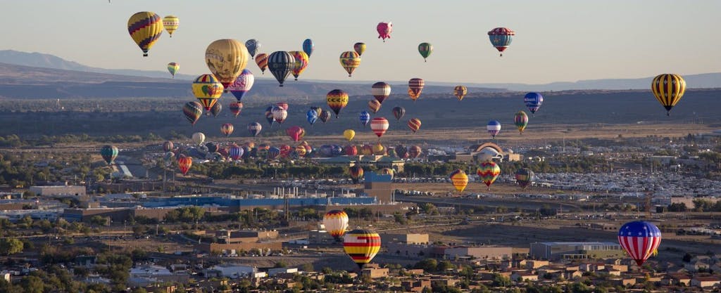 Brightly colored hot air balloons rise above the Albuquerque landscape during the annual festival in New Mexico, where residents must consider if they must file a New Mexico state tax return.