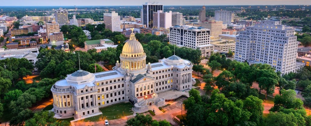 The state capitol building dominates the Jackson, Mississippi skyline at dusk.