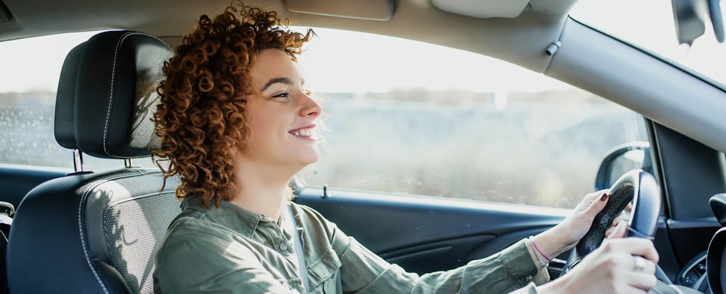 Woman driving her car and smiling