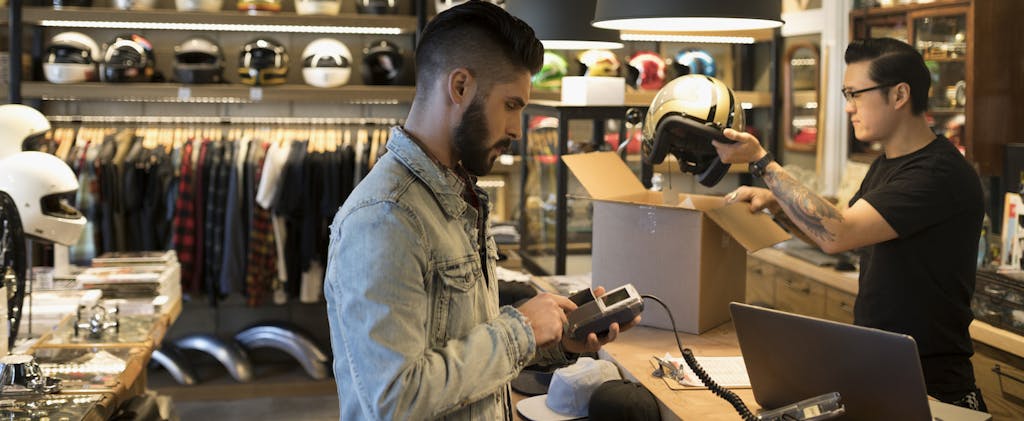 Man using credit card reader at counter in motorcycle shop