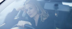 Woman driving with a thoughtful, serious expression
