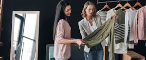 Young woman in a fashion boutique helping customer choose clothes