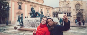 Two women posing in front of a fountain in Valencia
