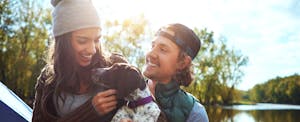 Couple camping by a lake with their dog