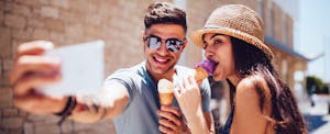 Young hipster couple eating ice-cream and taking selfies and going into dating debt