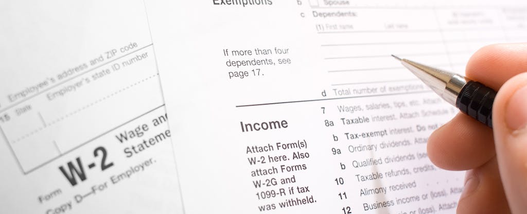 Closeup of somebody filling out tax forms with a pen
