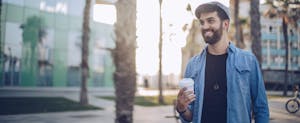 Young man standing on the street holding coffee cup