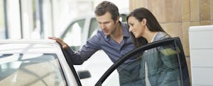 Couple looking inside car at showroom
