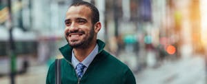 Young businessman standing on the street and smiling