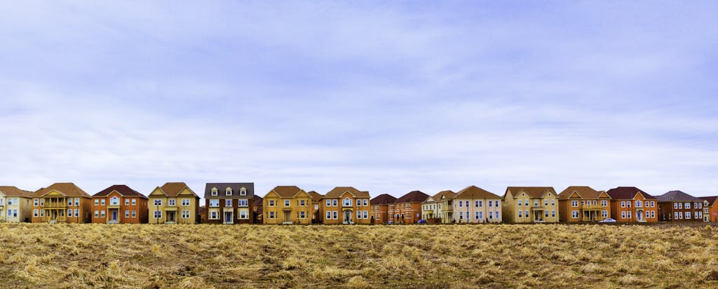 Houses in a row with a field in the foreground. Learn the average credit score to buy a house.