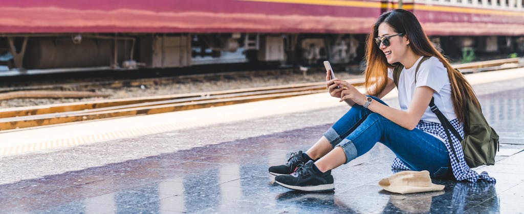 Young woman at train station using smartphone
