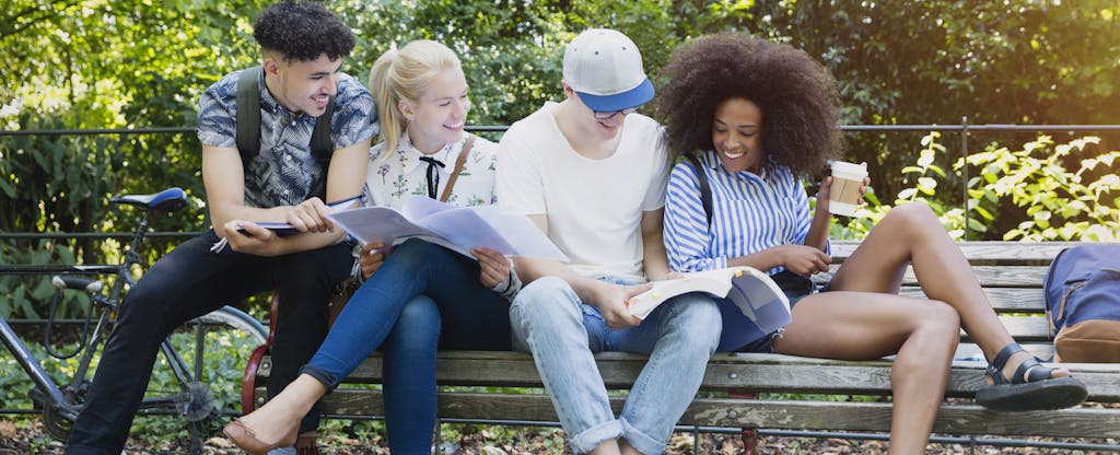 College students hanging out studying on park bench