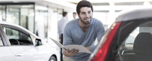 Smiling man looking at new car at car dealership