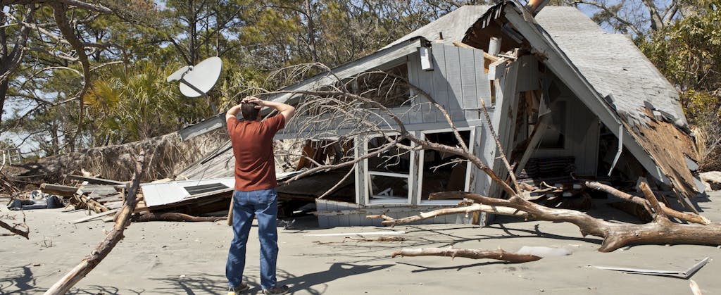 Man standing in front of his collapsed home, holding his head in his hands, may be able to take a casualty-loss deduction on his federal income taxes.