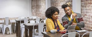 Young couple working on computer in coffee shop