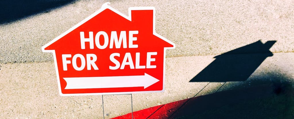 Closeup of a sign with the words "home for sale" and an arrow pointing to the right