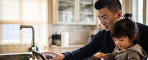 Man looking at tablet while sitting with his daughter in the kitchen