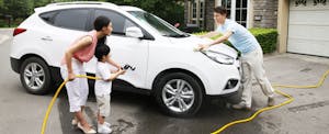 Parents and son washing their car in their driveway
