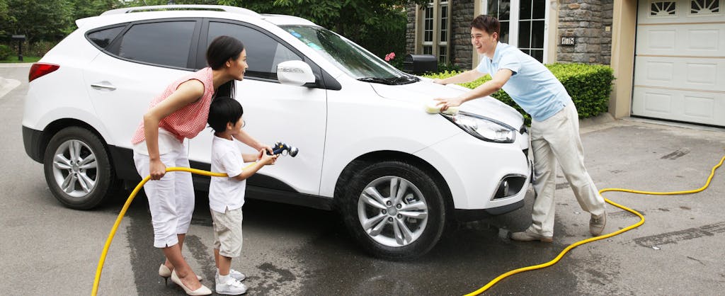 Parents and son washing their car in their driveway