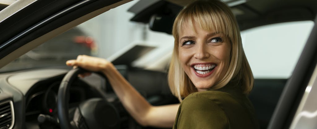 Woman sitting in a new car and smiling