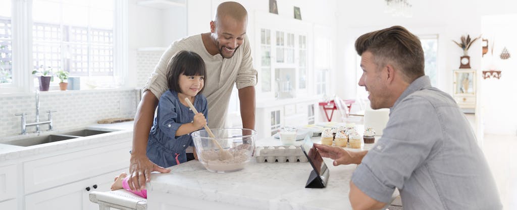Male same sex couple with adopted toddler daughter baking in kitchen