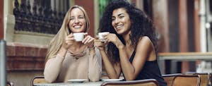 Two female friends having coffee at a sidewalk cafe