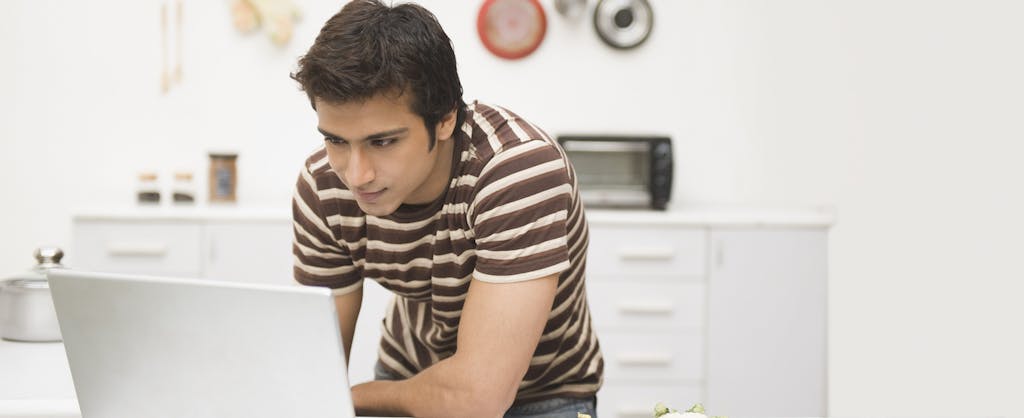 Man using a laptop on a kitchen counter