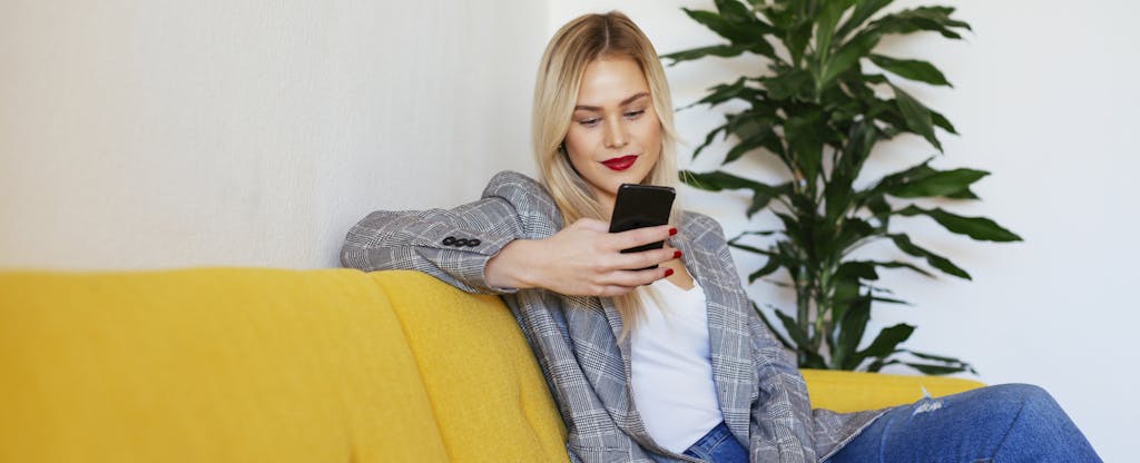 Woman sitting on a couch and reading her phone