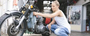 Young woman cleaning motorcycle