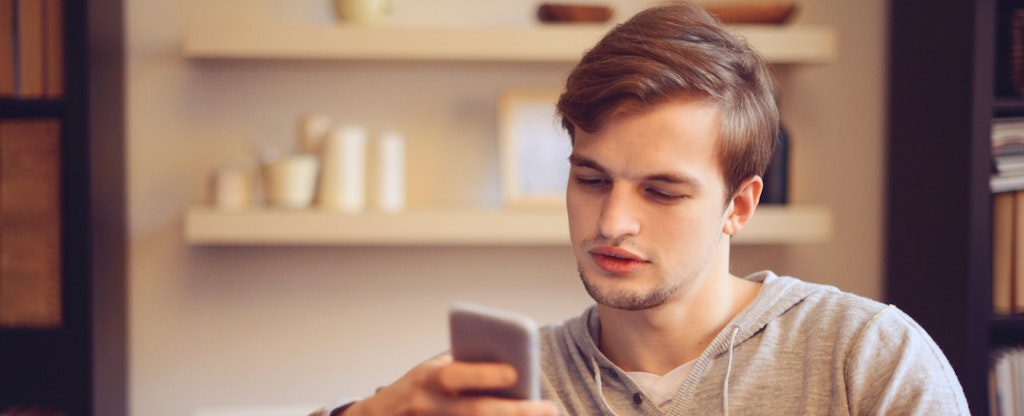 Man sitting in his living room, reading off of his phone